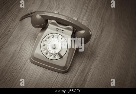 Vintage gray telephone on hardwood surface desk or floor. Stock Photo