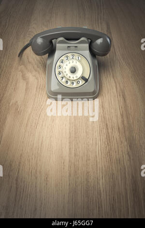 Vintage gray telephone on hardwood surface desk or floor. Stock Photo