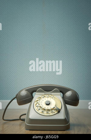 Gray vintage phone on hardwood floor and dotted light blue wallpaper on background. Stock Photo