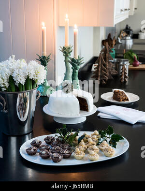 Small tarts and Christmas cake on a black stone worktop in elegant candle-lit kitchen Stock Photo