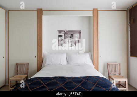 Zen-like bedroom with white laminate and oak, African textile as bed cover Stock Photo