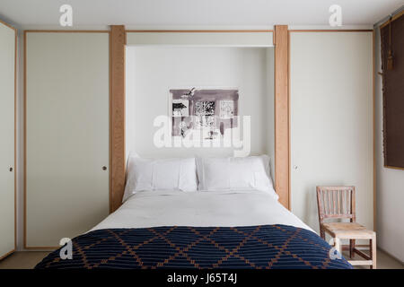 Zen-like bedroom with white laminate and oak, African textile as bed cover Stock Photo