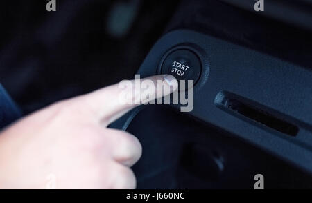 Driver hand pushes engine start stop button. Modern luxury car interior details Stock Photo