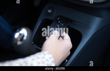 The man inserts the key card into the slot in the car to start the engine close up Stock Photo