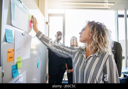 Diverse business team brainstorming in office looking at whiteboard Stock Photo