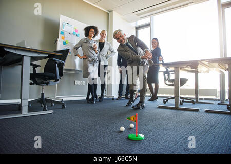 Business people teambuilding in office space with mini golf, laughing looking positive Stock Photo