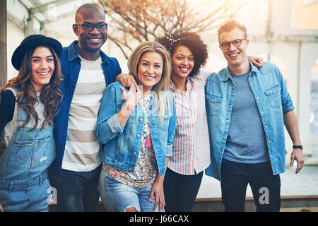 Happy group of black and white friends embracing and looking at camera spending time together. Stock Photo