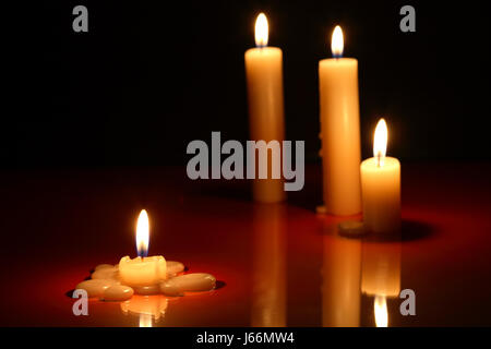Few lighting candles on dark background with reflection Stock Photo - Alamy