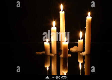 Few lighting candles on glass surface with reflection Stock Photo