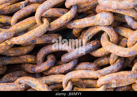 A frame full of thick, metal chain that is rusty, worn and weathered in an industrial background image. Stock Photo