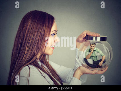 Woman holding a glass jar with imprisoned man in it Stock Photo