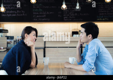 Dating in a cafe. Beautiful Asian lover couple sitting in a cafe enjoying in coffee and conversation. Love and romance. Stock Photo