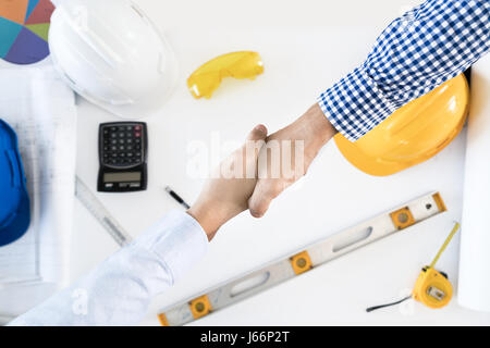 Top view Architect and engineer shaking hands, finishing up a meeting on building project and tools. Shaking hands agreement concept. Stock Photo