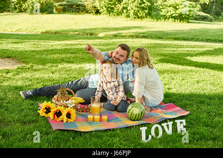 Young family have picknic in a park. Stock Photo