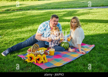 Young family have picknic in a park. Stock Photo