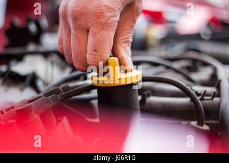 Mechanic checks the oil level in the engine, before pouring in the engine Stock Photo