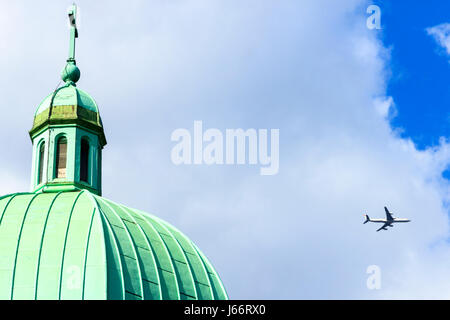 An aeroplane passes the green verdigris-covered copper dome of St Joseph's Church on Highgate Hill, London, UK Stock Photo
