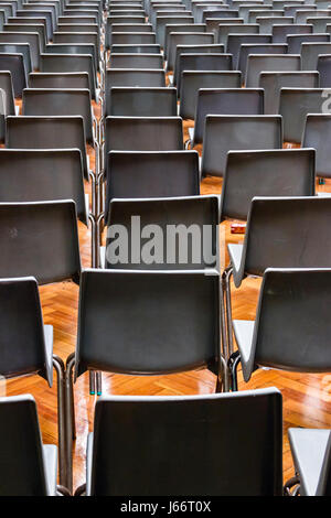 Grey plastic chairs laid out in rows for a concert or presentation in an empty hall or auditorium Stock Photo
