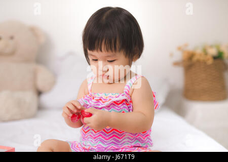 Little cute baby girl sitting on bed with grapes Stock Photo