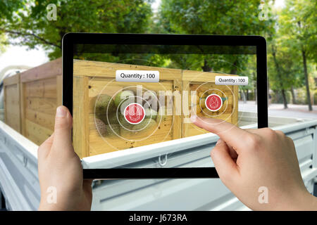 Logistic , Augmented reality marketing , X-Ray packages concept. Hand holding tablet to check fruit inside boxes in pick-up truck car with Bluetooth s Stock Photo