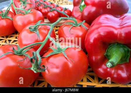 Fresh red vegetables on a wooden background and straw mat. Stock Photo