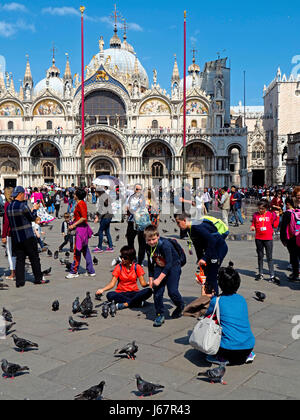 Tourists feeding pigeons in Saint Mark's Square (Piazza San Marco) in Venice (Veneza). Stock Photo