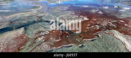 Bright colorful natural abstraction: a sand texture on the shore of a salty lake red, blue, green, yellow, white, color changing into each other. Stock Photo