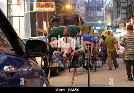 A hand rickshaw puller waits for passengers in his rickshaw in Kolkata on February 10, 2016. Stock Photo