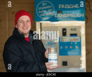 Heuchelheim, Germany. 20th Apr, 2017. Farmer Thorsten Klug holds up a glass container for milk in front of his milk vending machine in Heuchelheim, Germany, 20 April 2017. Klug has invested some 20,000 euros in a milk vending machine and a corresponding parking spot. Customers can now get milk for 1 euro per litre from a tap whenever they feel like it. Photo: Andreas Arnold/dpa/Alamy Live News Stock Photo