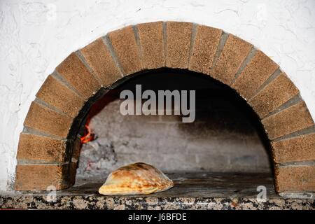 Freshly cooked Calzone in a wood fired oven, Hersonissos, Crete, Greece, Europe. Stock Photo