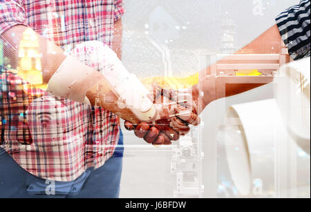 Industry 4.0 internet of things concept. Double exposure of Two Engineers man shake hands , automation wireless robot machine arm and circuit boards b Stock Photo