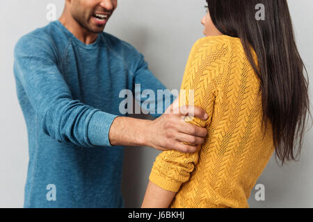 Cropped image of agressive man and frightened woman isolated over grey background Stock Photo