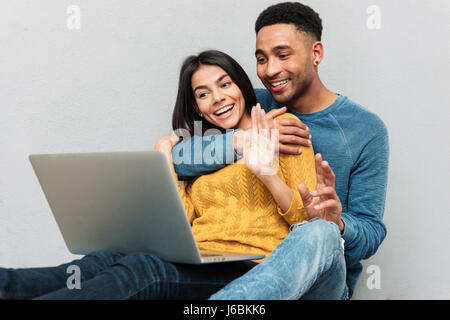 African smiling man hugging woman while she using laptop isolated Stock Photo