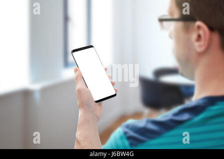 Guy with glasses work on modern smart phone. View behind shoulder. Isolated white screen for mockup. Stock Photo