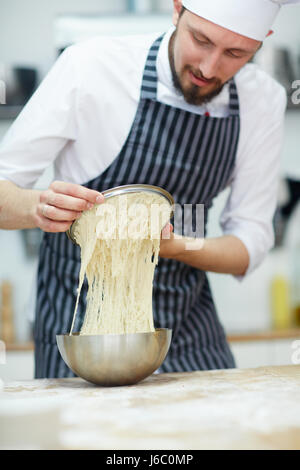 Man in chef uniform making dough for bread or pastry Stock Photo