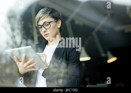 Portrait of young woman with creative haircut using digital tablet for planning work in office Stock Photo