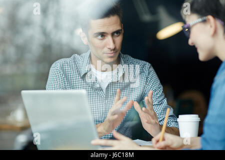 Portrait of young man sharing ideas with colleague during work meeting creative teams office Stock Photo
