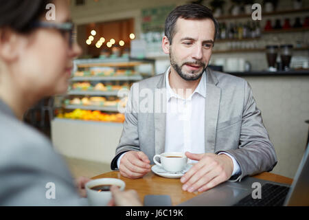 Two modern traders discussing online data while sitting in cafe Stock Photo