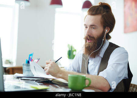 Portrait of trendy bearded man video chatting with business partners working in modern office Stock Photo
