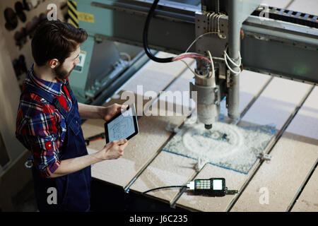 Factory worker operating cutter machine using digital tablet in workshop Stock Photo