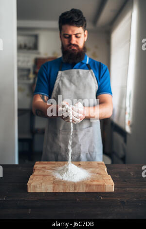 Male chef in apron with flour in hands working on cutting board. Bread cooking Stock Photo