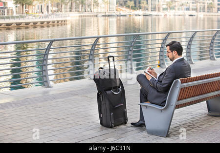 Businessman sitting and taking notes in Dubai Marina, UAE Stock Photo