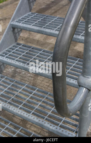 Set of three galvanized industrial safety steps with handrail. Stock Photo