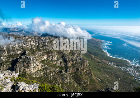 View from Table Mountain, Cape Town, South Africa, towards the sea and coast road with cloud formation known as the tablecloth over twelve Apostles Stock Photo