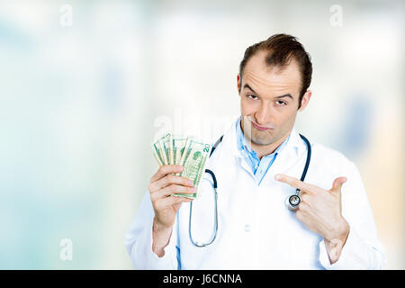 Healthcare financial system concept. Greedy miserly health care professional, male doctor holding money dollar bills standing in hospital clinic hallw Stock Photo