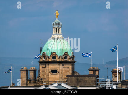 View of copper dome and spire on top of Bank of Scotland headquarters, The Mound, Edinburgh, Scotland Uk, with waving saltire St Andrews Cross flags Stock Photo