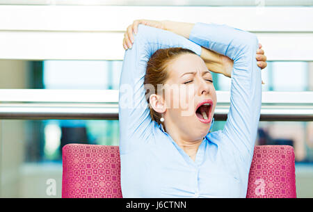 Its is too early for this meeting. Closeup portrait sleepy young business woman, sitting in armchair wide open mouth yawning, eyes closed, looking bor Stock Photo