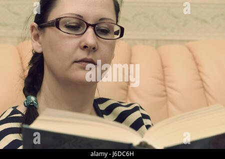 A woman is reading a book on the couch. Vintage. Stock Photo