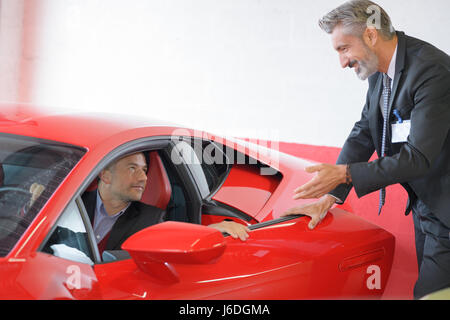 Salesman showing sports car to customer Stock Photo