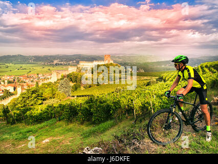 Cyclist admires from the hill the Soave castle views. Stock Photo